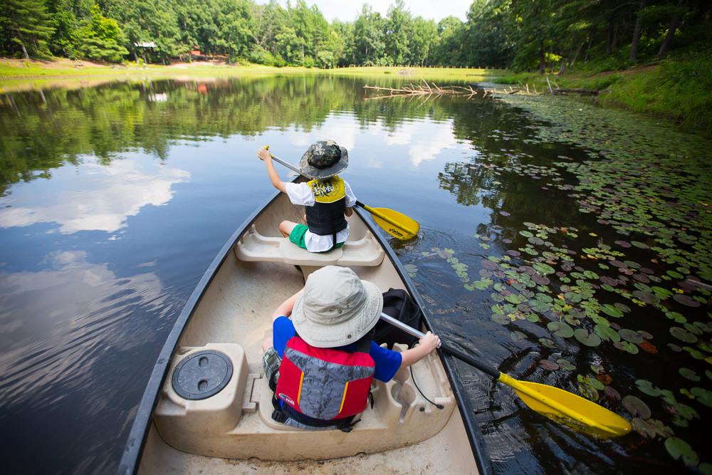 a woman and child paddling in a canoe down a river 