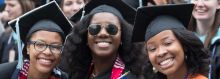 Three female african american students at gradation with caps and gowns