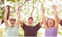 three senior citizens with arms raised over head hold hands in victory