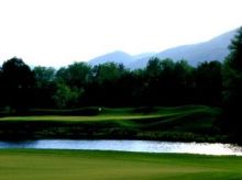 Golf course in Charlottesville with greens, water, and mountains in the distance